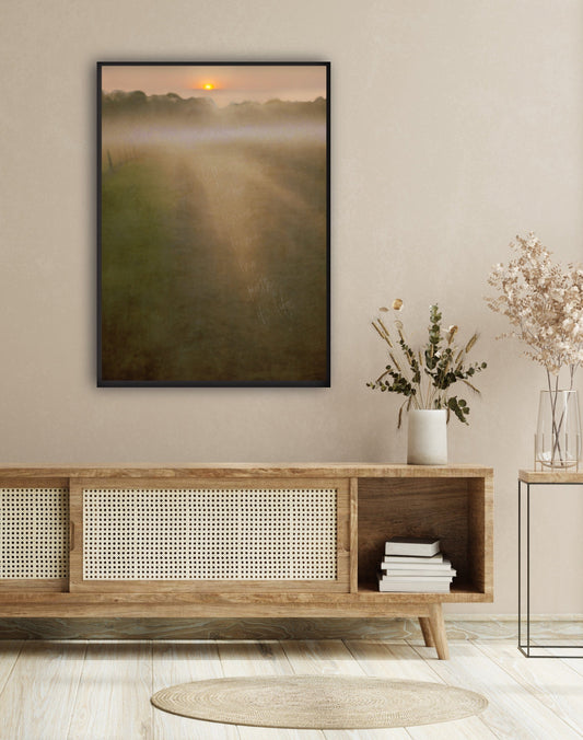 Muted soft earthy landscape of narrow road in a field with rising sun and mist in distance